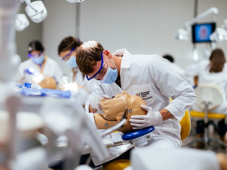 A person in a white coat and mask holding a mannequin

AI-generated content may be incorrect.